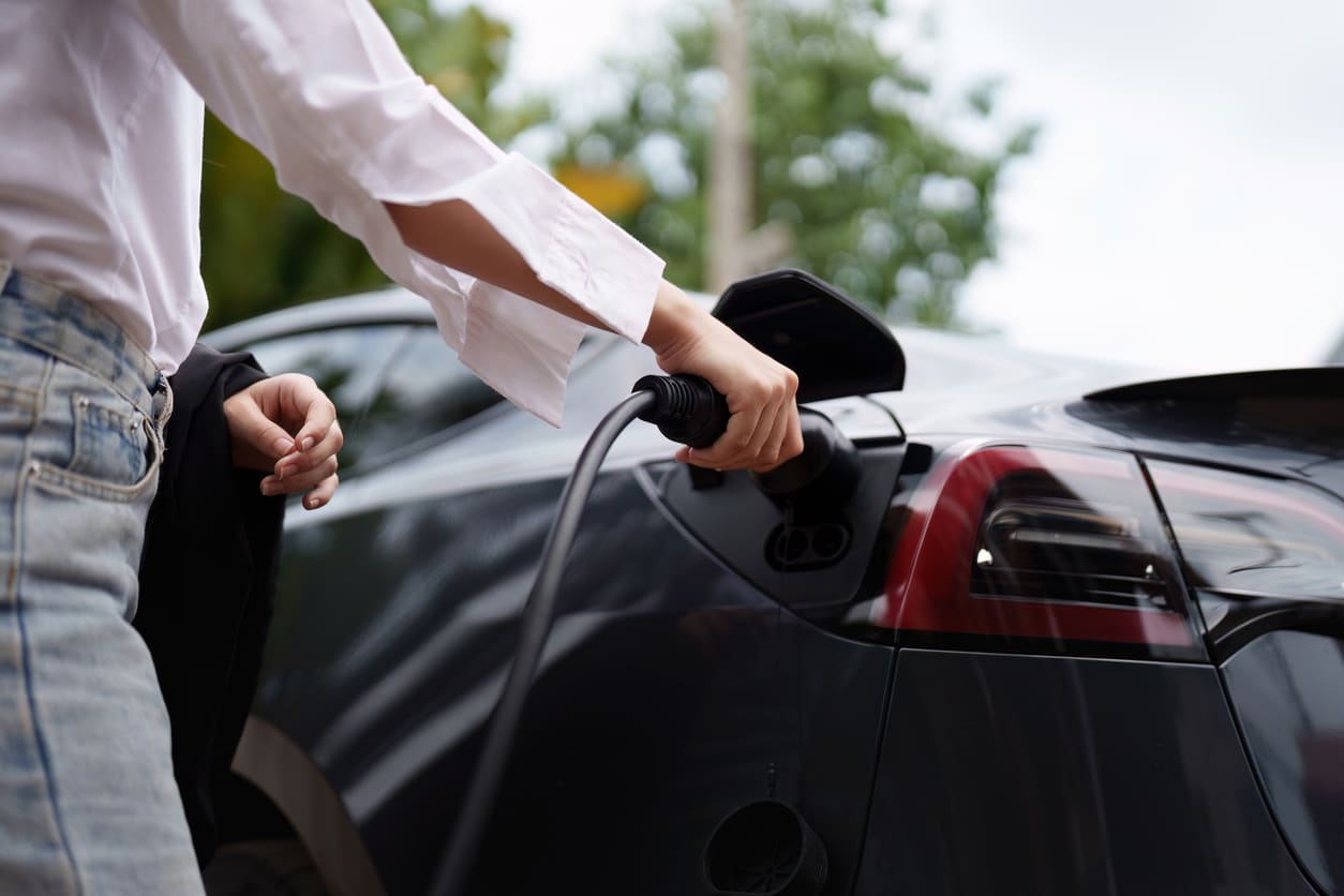 A person charging an electric car outdoors.